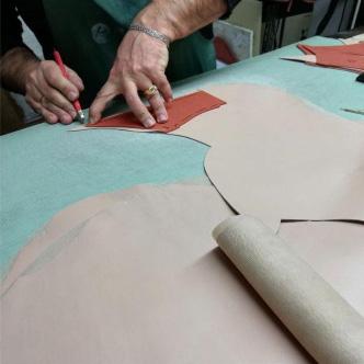 Precision cutting of red leather with template - Kendrick manufacturing process
